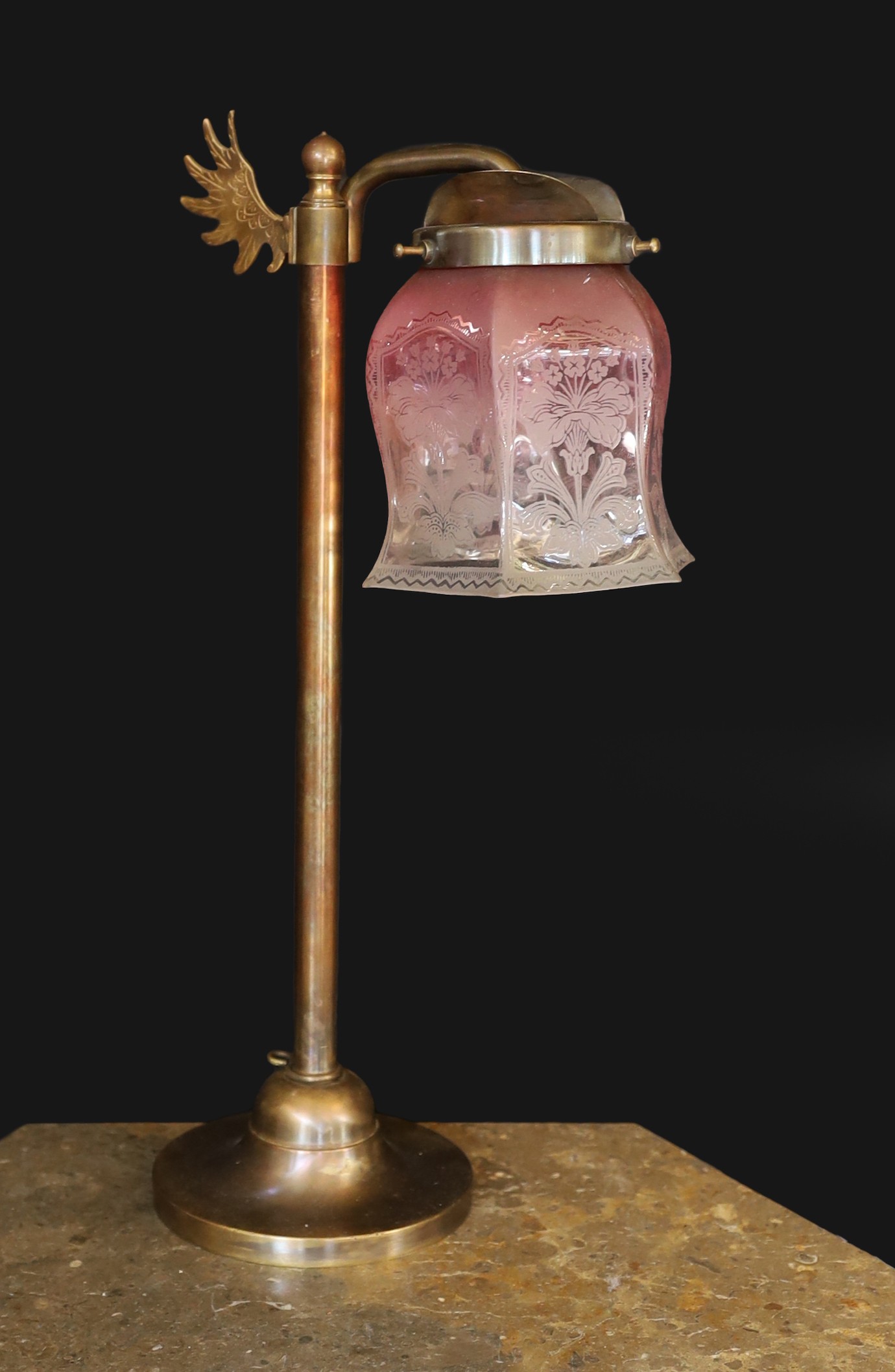 An Edwardian style bronze metal desk lamp with angel wing motif and cranberry tinted etched glass shade, height 49cm
